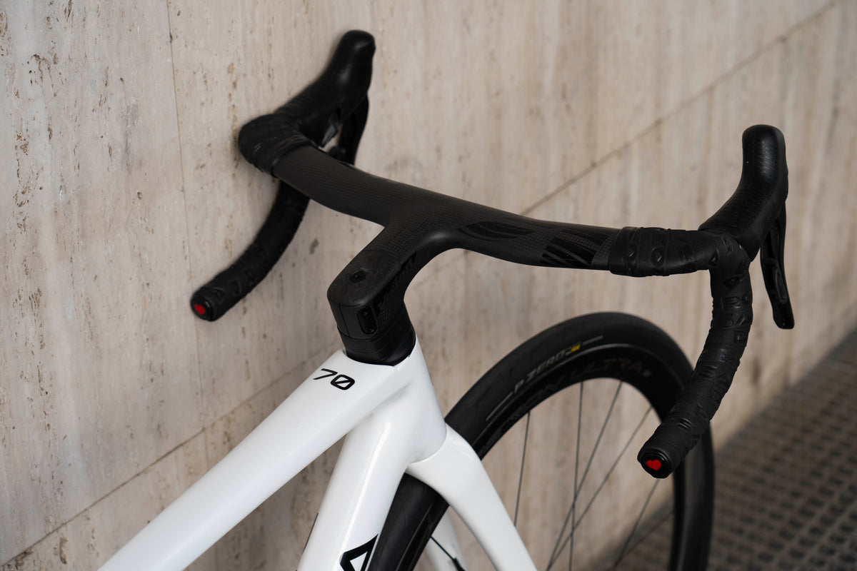 Close-up of the integrated carbon handlebar and clean white aero cockpit setup on the De Rosa 70 anniversary complete bicycle by Cicli Corsa.